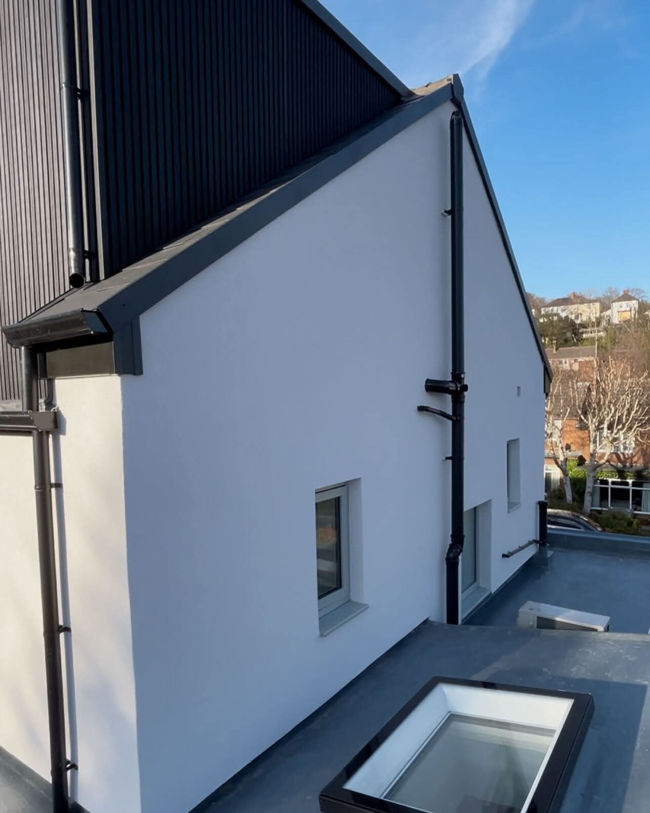 Smooth rendered gable end with neat black rainwater goods