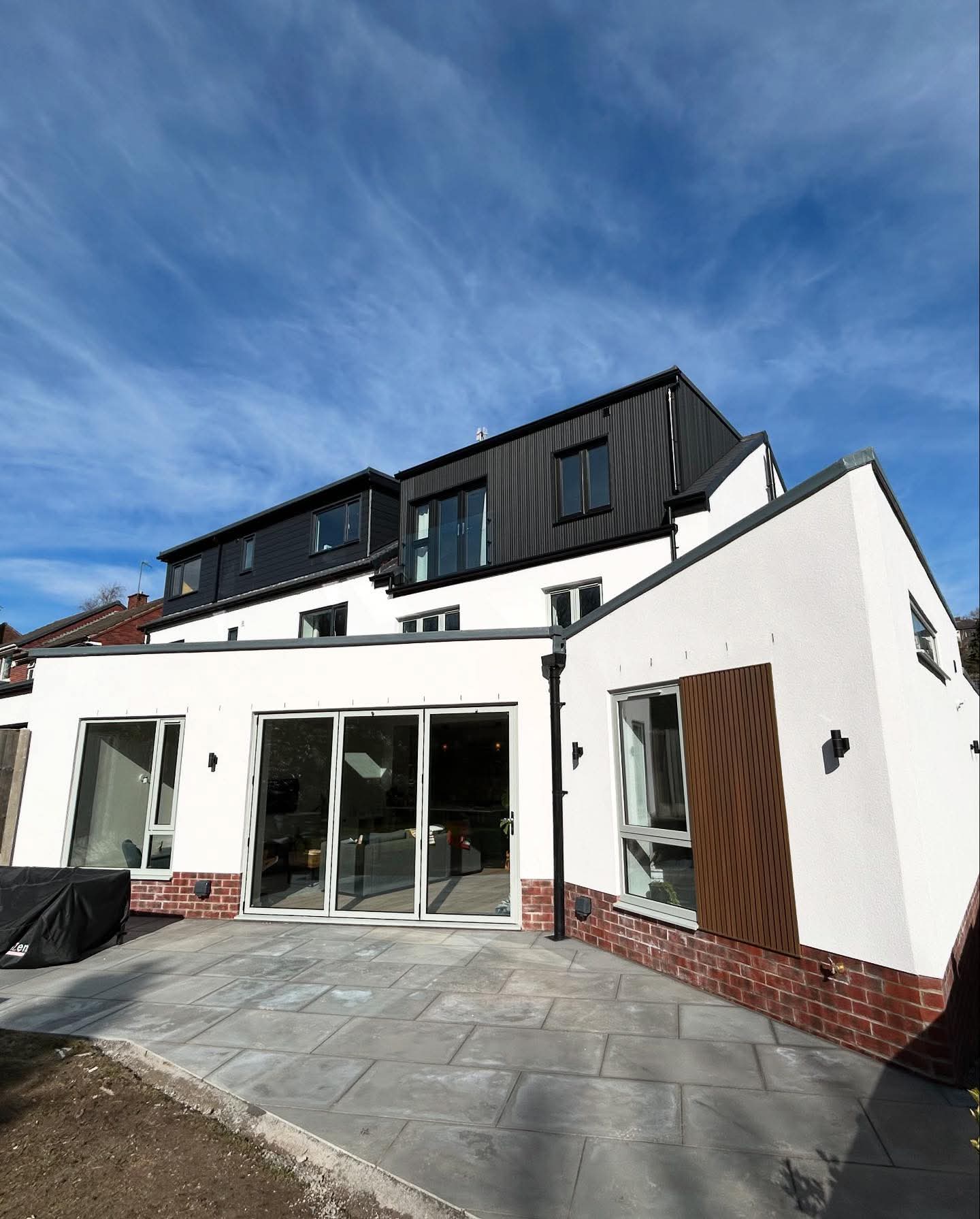 Fresh white render on a rear extension with bifold doors and a new patio