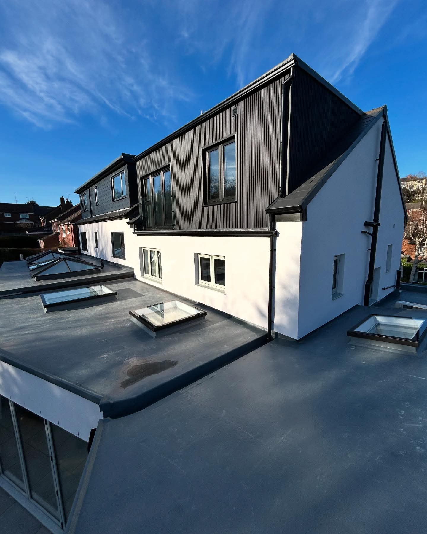 Newly rendered gable and dormer with dark cladding and roof lanterns
